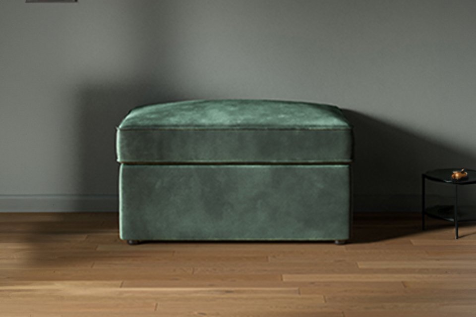 A green Jay-Be® Footstool chair bed in a living room setup.